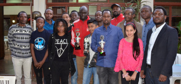 Happy prize winners of the 61st Nairobi Chess Club Championship pose for a group photo with Arbiter IA Duke Micheka (extreme right).