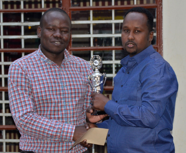 Adan Abdul Roba (right) proud winner of the U1800 Section receives his trophy from CEO of Nairobi Chess Academy FM Steve Ouma. Photo credit Kim Bhari.